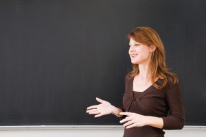 Young teacher lectures in front of the blackboard with plenty of space for copy space
